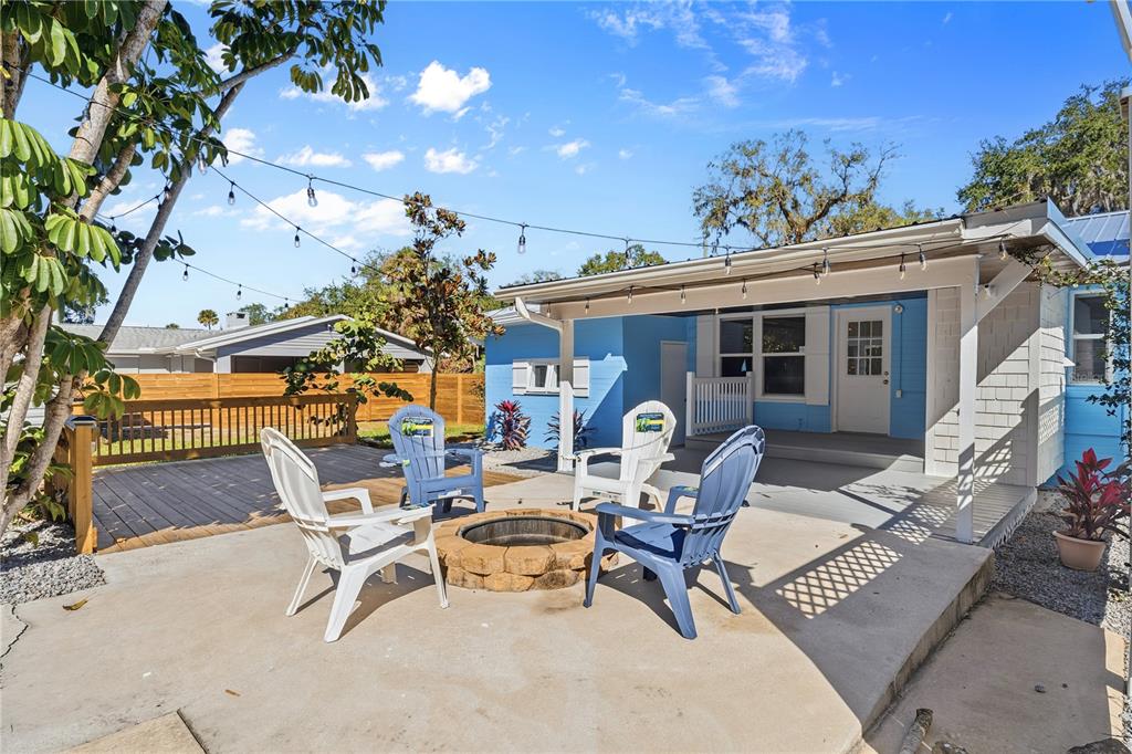A blue house features a concrete patio with a stone fire pit and four chairs — 1000 FAULKNER STREET, NEW SMYRNA BEACH, FL