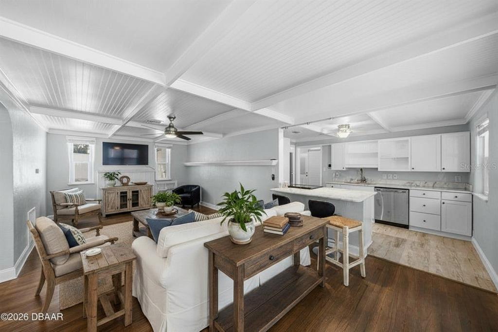 An open-concept living room and kitchen featuring white cabinetry, wood flooring, and coffered ceilings — 1000 FAULKNER STREET, NEW SMYRNA BEACH, FL