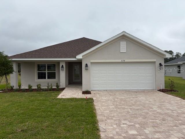 A single-story house with a beige stucco exterior, a two-car garage, and a paver driveway — 7174 SW 179TH COURT ROAD, DUNNELLON, FL