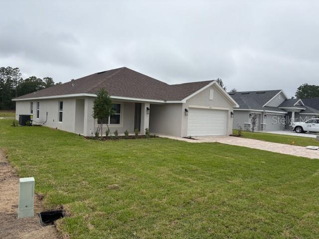 A single-story house with a beige stucco exterior, a brown roof, and a two-car garage — 7174 SW 179TH COURT ROAD, DUNNELLON, FL