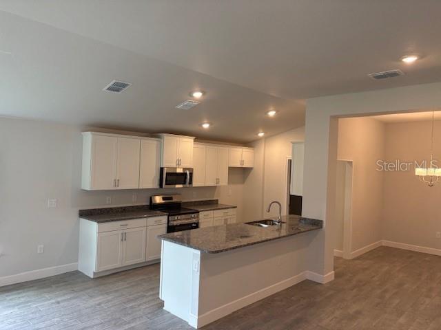 A kitchen features white cabinets, granite countertops, a center island, and light-colored wood-look flooring — 7174 SW 179TH COURT ROAD, DUNNELLON, FL