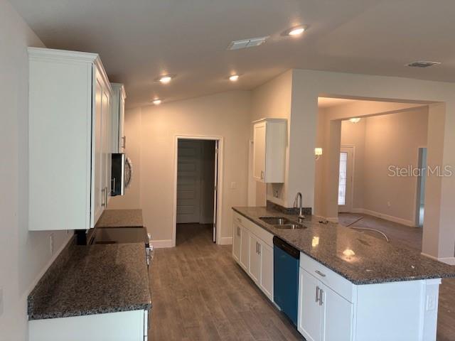 A kitchen features white cabinets, granite countertops, and a center island with a blue dishwasher — 7174 SW 179TH COURT ROAD, DUNNELLON, FL