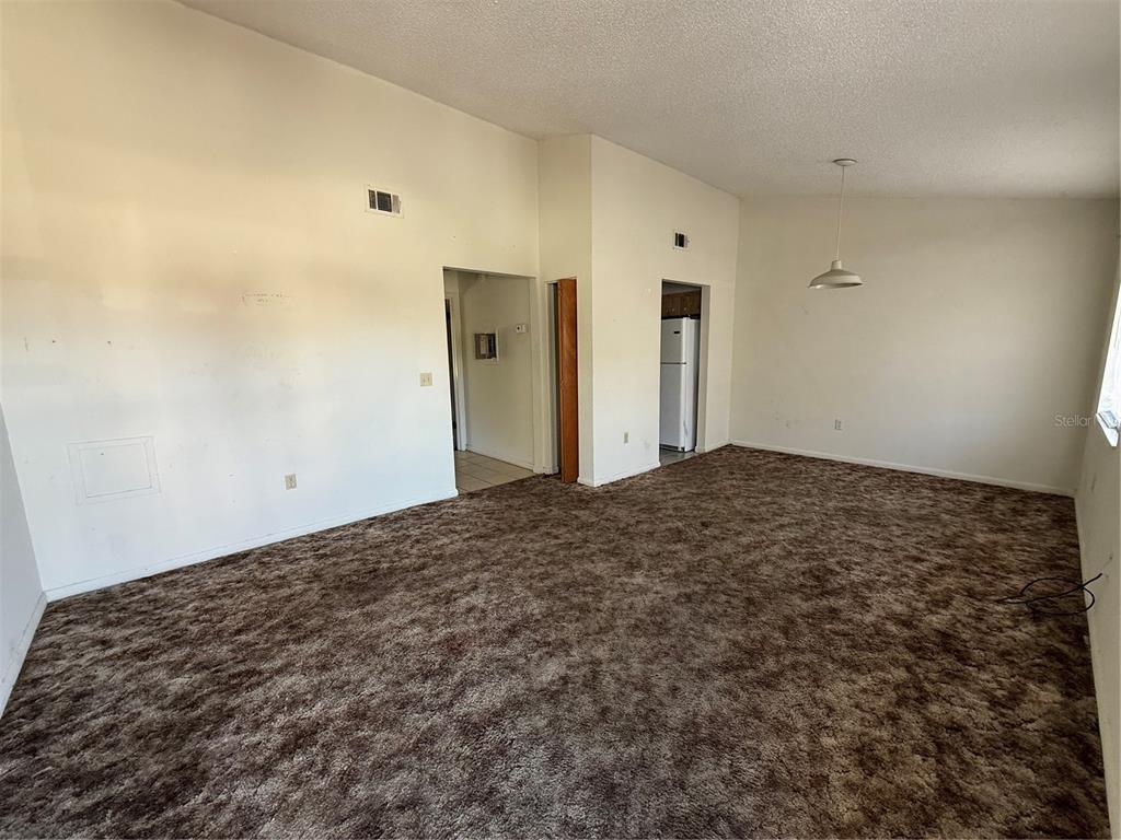 A living room features beige walls, a vaulted ceiling, and brown patterned wall-to-wall carpeting — 3032 SE 5TH TERRACE UNIT F, OCALA, FL