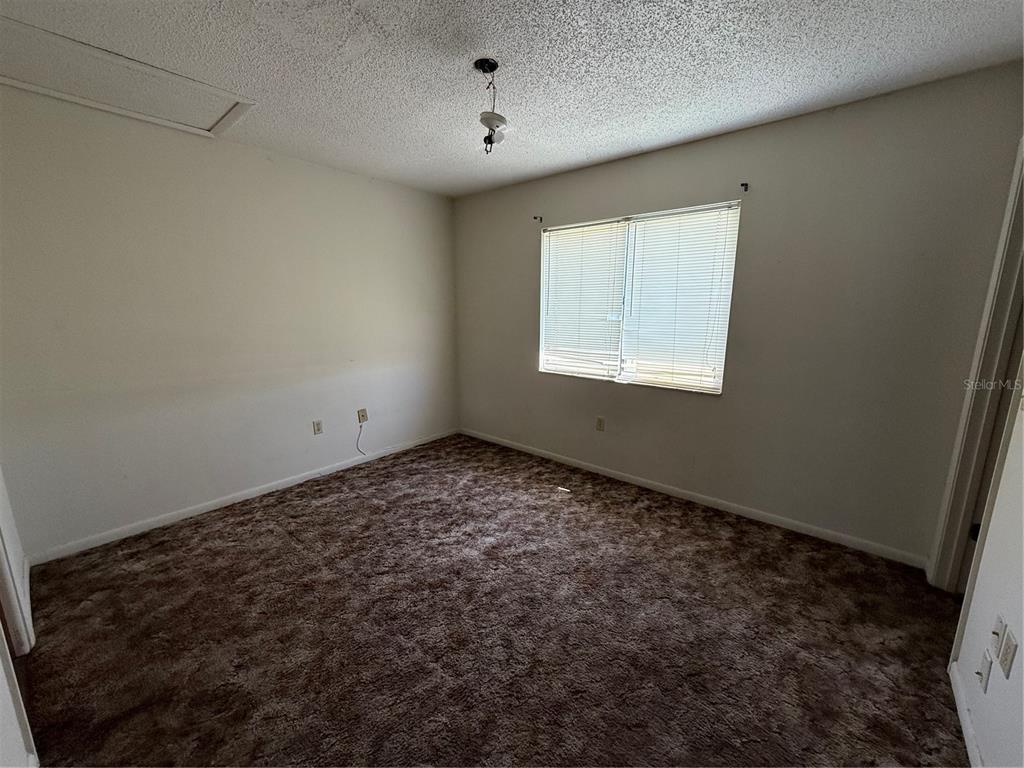 An empty bedroom features brown wall-to-wall carpeting, white walls, and a single window with blinds — 3032 SE 5TH TERRACE UNIT F, OCALA, FL