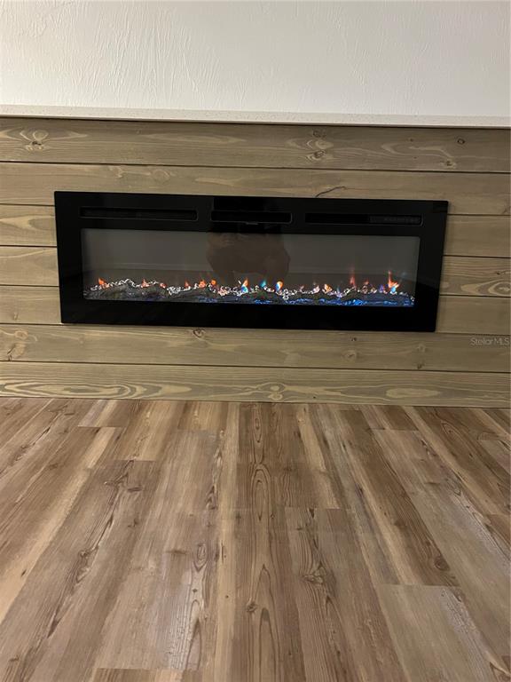 A wall-mounted electric fireplace is centered on a horizontal wood-paneled accent wall above wood-look flooring — 79 CYPRESS POND ROAD UNIT 79, PORT ORANGE, FL