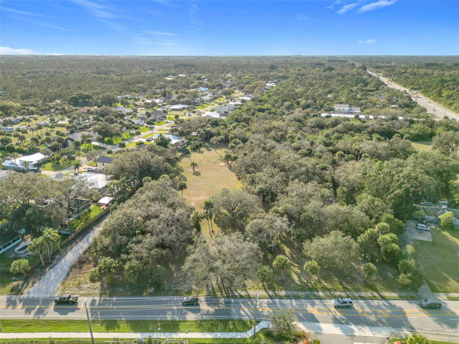 An aerial view shows a vacant, wooded lot situated between residential houses and a road — 995 Old Dixie Highway, Vero Beach FL 32962, VERO BEACH, FL