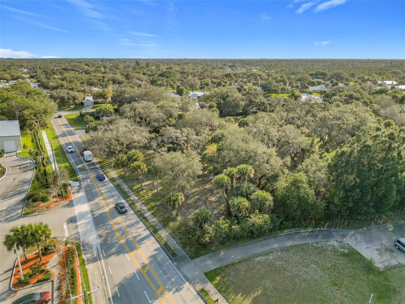 An aerial view shows a wooded lot adjacent to a paved road with passing vehicles — 995 Old Dixie Highway, Vero Beach FL 32962, VERO BEACH, FL