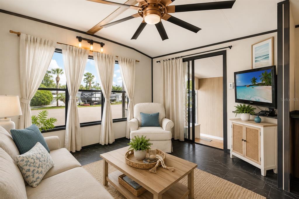 A living room with a ceiling fan, tiled floors, a sofa, and a television — 9000 US HIGHWAY 192 UNIT 11, CLERMONT, FL