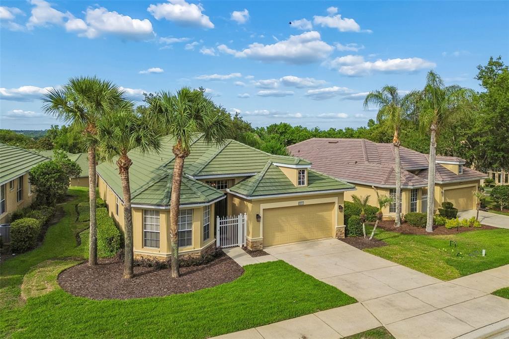 An aerial view of a tan house with a green tile roof and palm trees — 13128 PALMILLA CIRCLE, DADE CITY, FL
