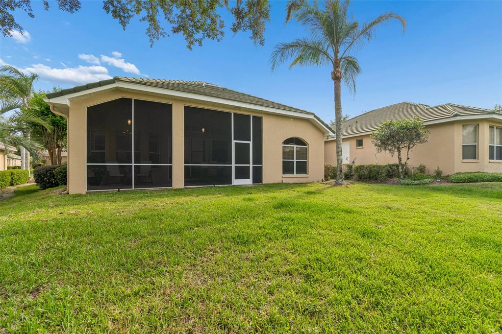 A tan house with a screened-in lanai and a palm tree in the backyard — 13128 PALMILLA CIRCLE, DADE CITY, FL