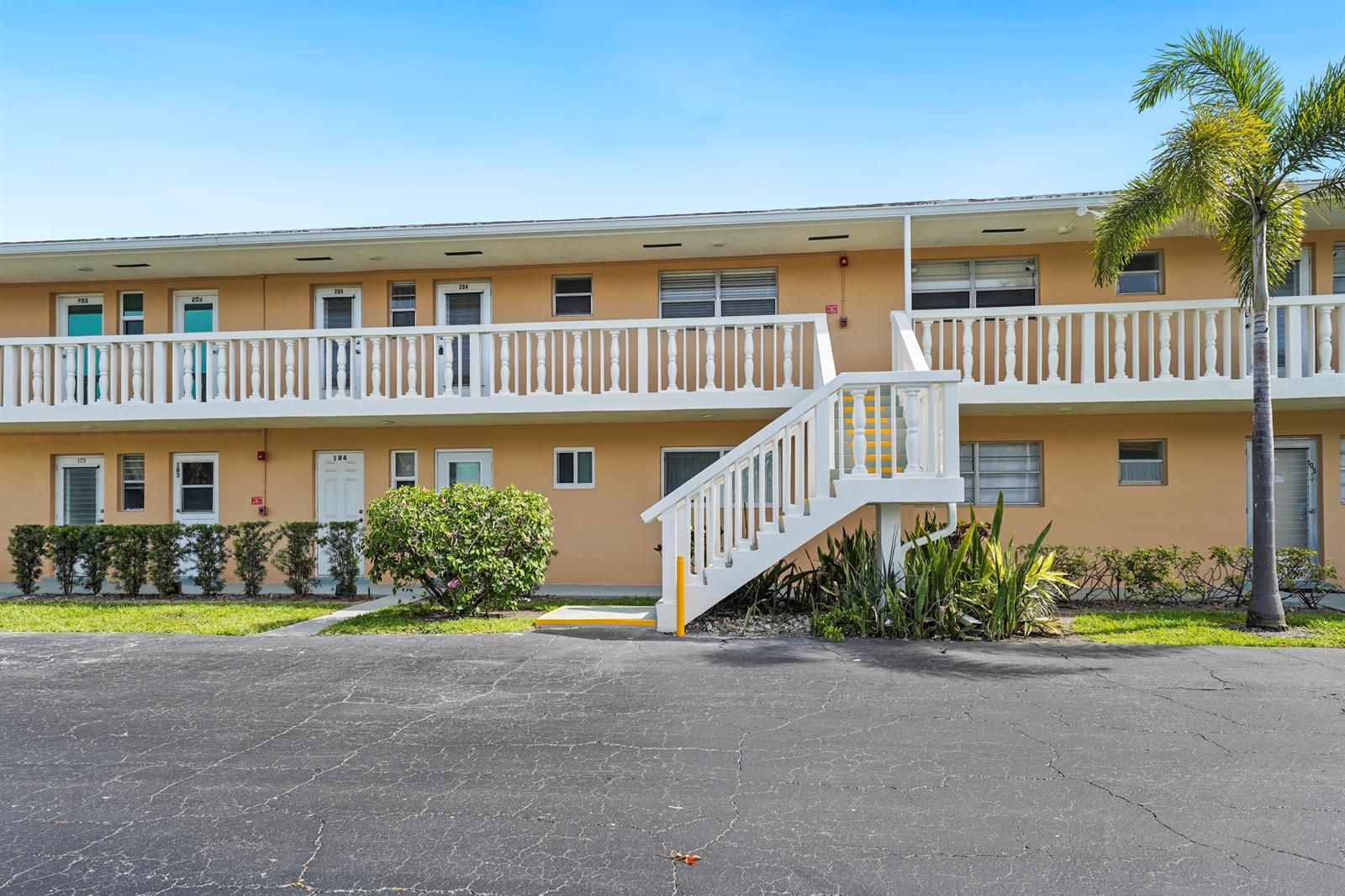 A two-story apartment building features a white balcony, an exterior staircase, and a palm tree — 2222 NE 1st Way # 204, Boynton Beach FL 33435, BOYNTON BEACH, FL