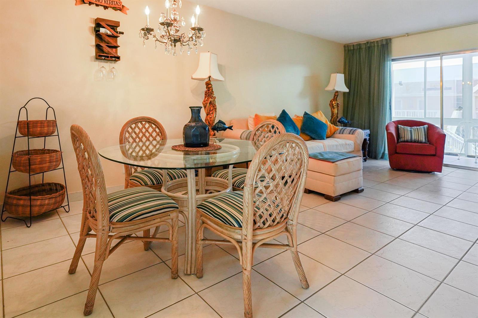 A dining area with a glass table and wicker chairs sits before a living room — 2222 NE 1st Way # 204, Boynton Beach FL 33435, BOYNTON BEACH, FL
