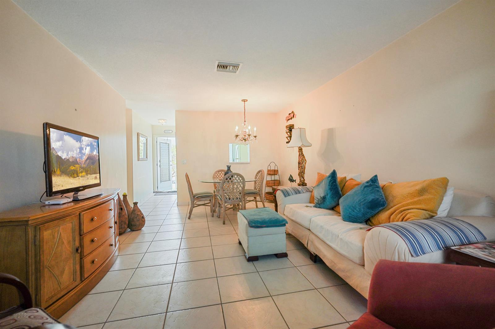 A living and dining area with tile floors, a white sofa, and a glass dining table — 2222 NE 1st Way # 204, Boynton Beach FL 33435, BOYNTON BEACH, FL