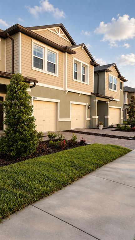 Exterior view of a multi-story townhouse complex with beige siding and attached garages — 9094 GALLANTREE PLACE, LAND O LAKES, FL