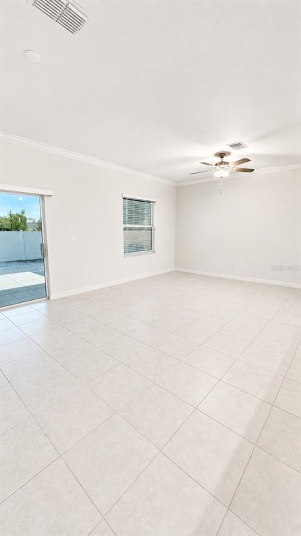 An empty room features light-colored tile flooring, a ceiling fan, and a sliding glass door — 9094 GALLANTREE PLACE, LAND O LAKES, FL