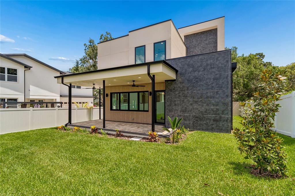 The exterior of a modern two-story house features a covered patio and a grassy backyard — 1305 HILTON PLACE, TAMPA, FL