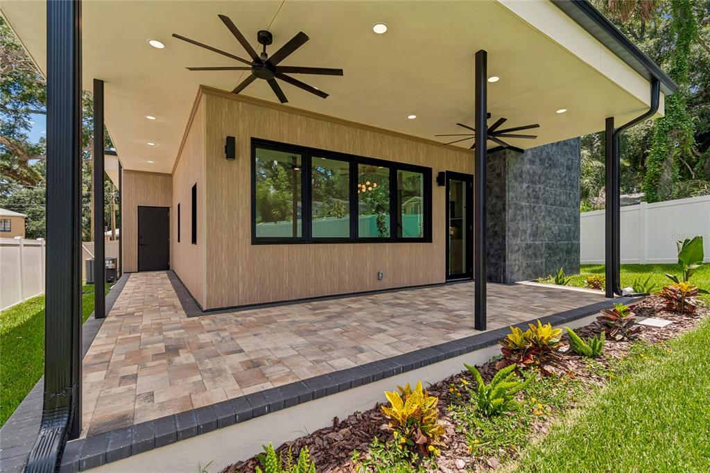A covered patio with paver flooring, black support columns, and wood-look siding on the exterior — 1305 HILTON PLACE, TAMPA, FL