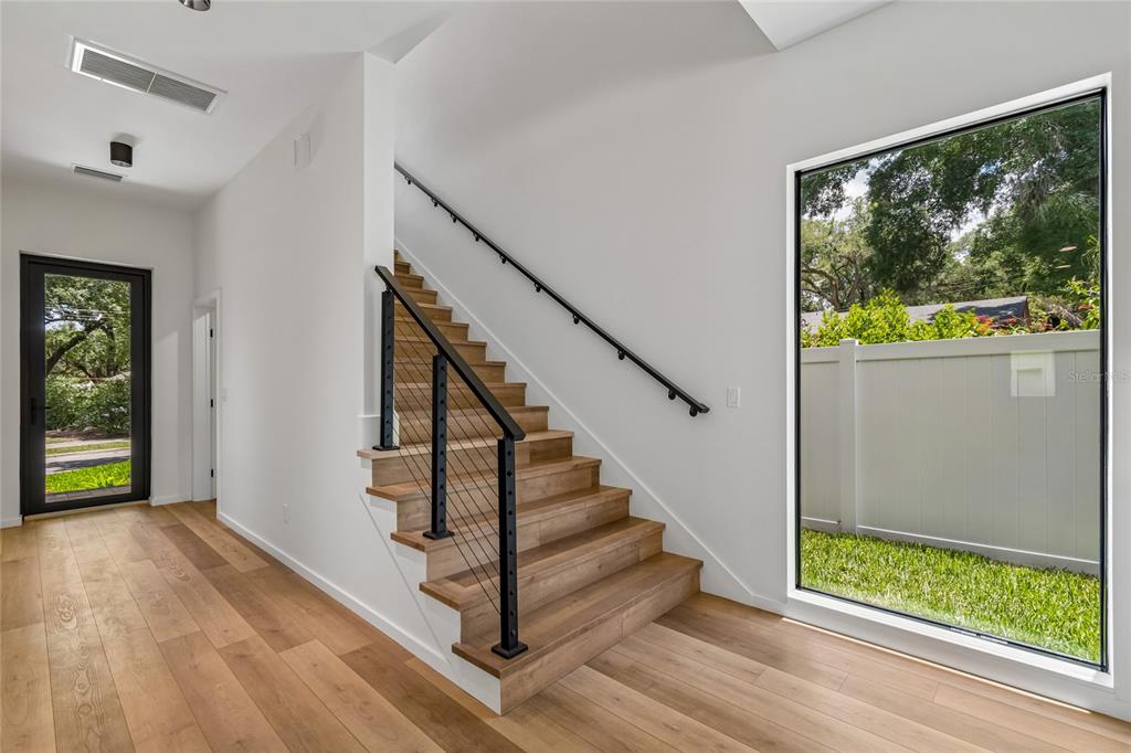 A modern staircase with wooden treads and cable railings sits beside a large window — 1305 HILTON PLACE, TAMPA, FL