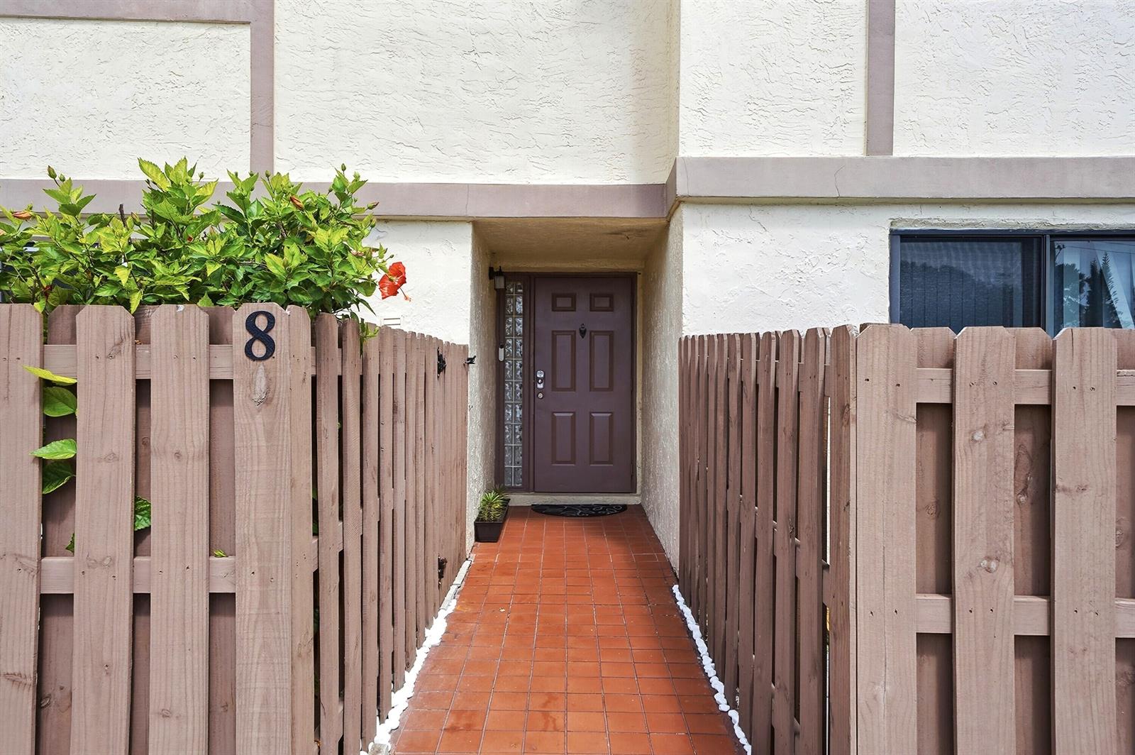 A brown front door is accessed by a tiled walkway between two wooden privacy fences — 10875 NW 29th Manor # 8, Sunrise FL 33322, SUNRISE, FL