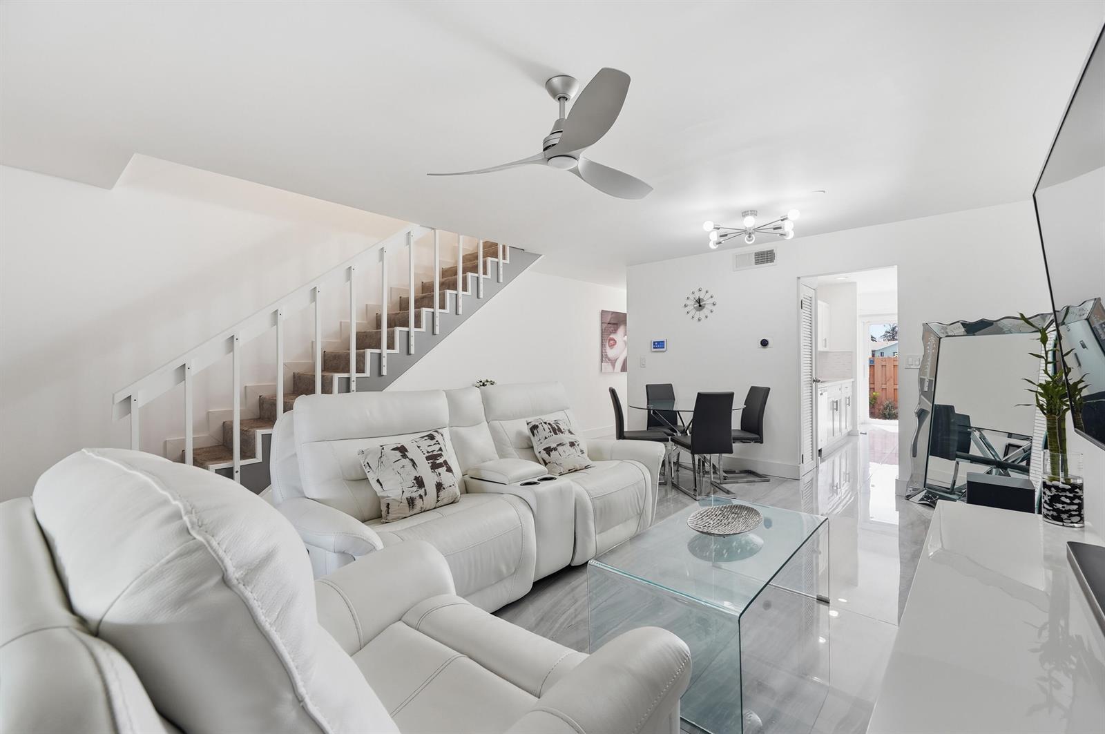 A modern living room features white leather sofas, a glass coffee table, and a staircase — 10875 NW 29th Manor # 8, Sunrise FL 33322, SUNRISE, FL