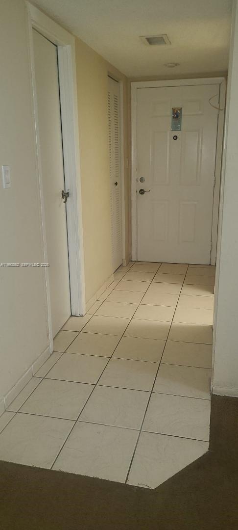 A tiled entryway leads to a white front door with two adjacent closet doors — 18101 NW 68th Ave # C206, Hialeah FL 33015, HIALEAH, FL