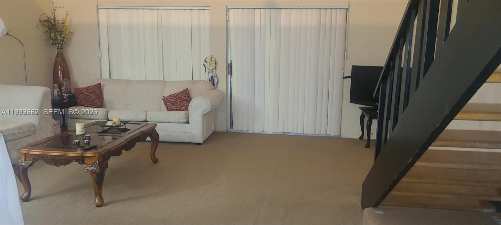 A living room features a beige sofa, a wooden coffee table, and a staircase — 18101 NW 68th Ave # C206, Hialeah FL 33015, HIALEAH, FL