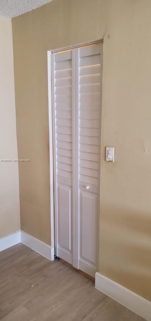 A narrow white louvered bifold closet door is set into a beige wall — 18101 NW 68th Ave # C206, Hialeah FL 33015, HIALEAH, FL