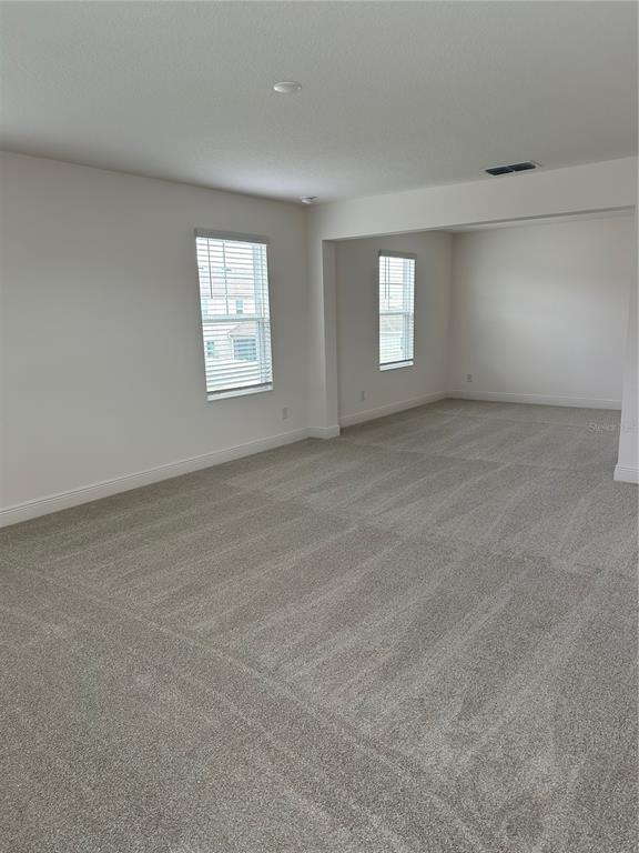 An empty room with gray carpet, white walls, and two windows — 7737 SCICLI WAY, CLERMONT, FL