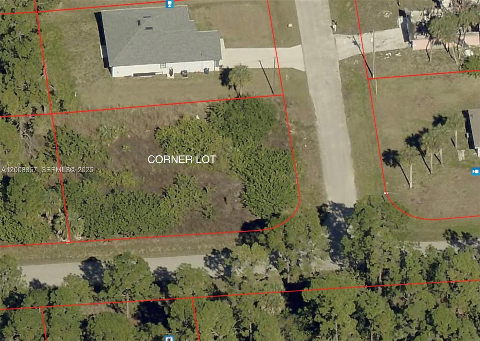 This aerial view shows a vacant corner lot with vegetation next to a paved road — 542 OAKFIELD AVE, Lehigh Acres FL 33974, LEHIGH ACRES, FL