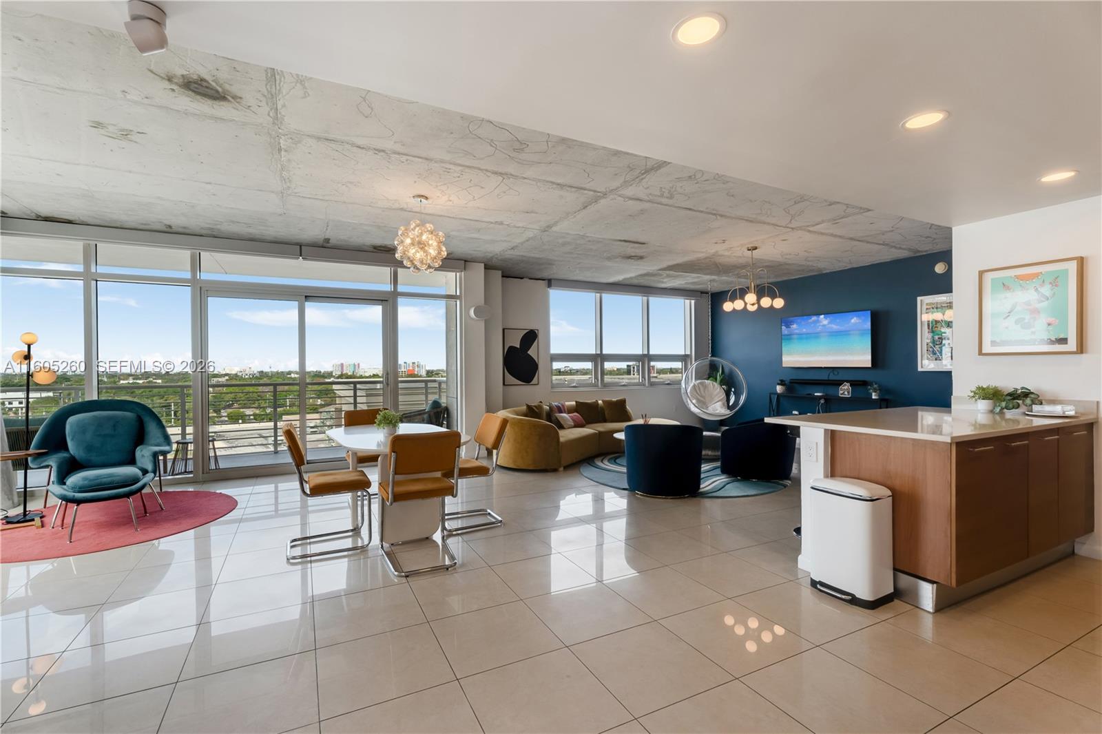 A modern open-concept living and dining area features a concrete ceiling and floor-to-ceiling windows — 3250 NE 1st Ave # 715, Miami FL 33137, MIAMI, FL