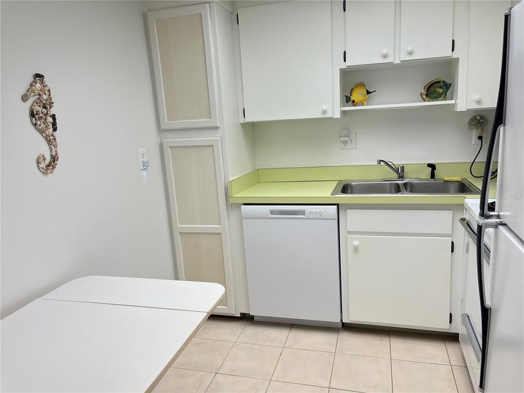 A kitchen features white cabinets, a light green countertop, a dishwasher, and a sink — 612 BIRD BAY DRIVE S UNIT 112CAR, VENICE, FL
