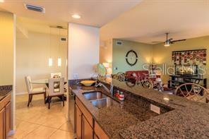 A kitchen with granite countertops overlooks a dining area and a living room — 7911 GRAND ESTUARY TRAIL UNIT 103, BRADENTON, FL