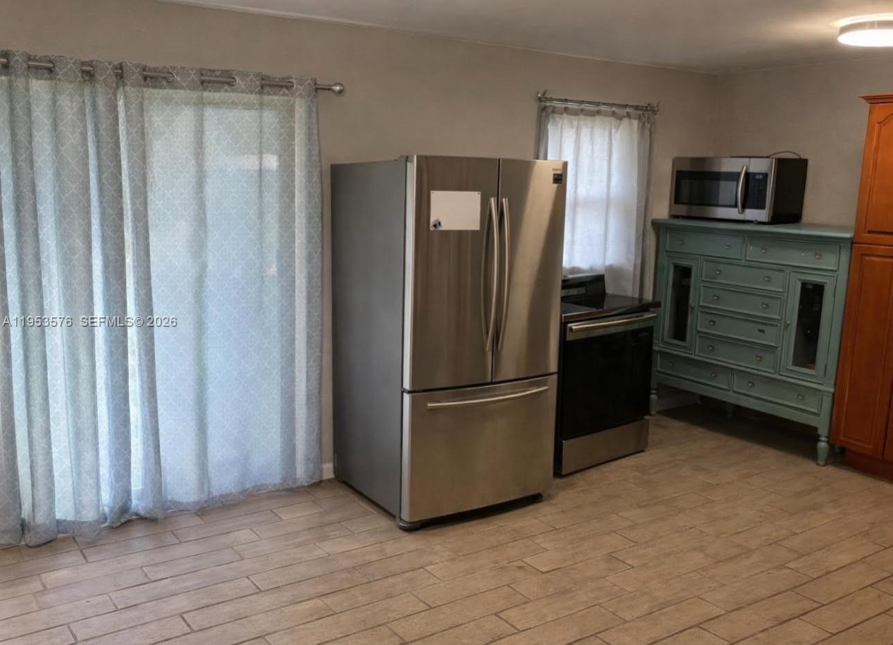 A kitchen features a stainless steel refrigerator, a stove, and a light blue wooden cabinet — 10010 SW 161st St, Miami FL 33157, MIAMI, FL