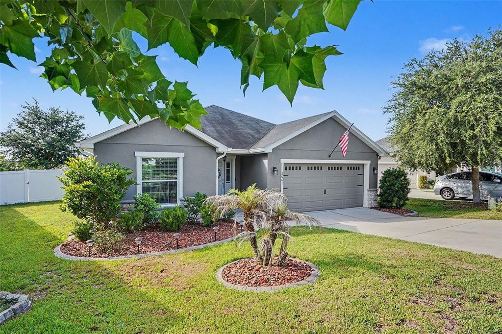 A gray single-story house with a two-car garage and a landscaped front yard — 2061 NIGHTHAWK DRIVE, HAINES CITY, FL