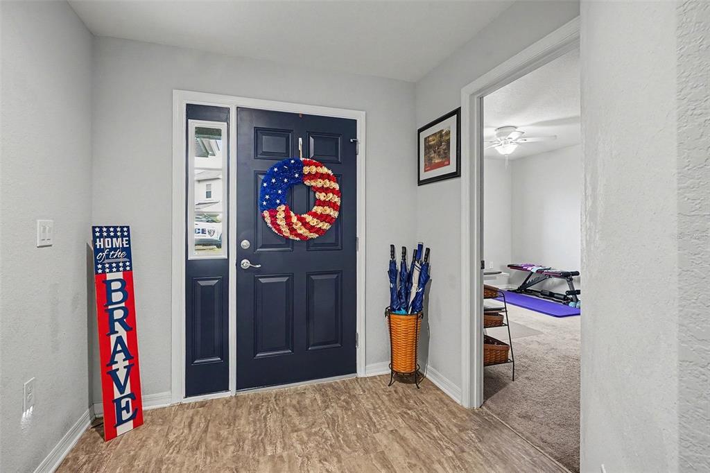 An entryway with a dark blue front door, a patriotic wreath, and an adjacent room — 2061 NIGHTHAWK DRIVE, HAINES CITY, FL