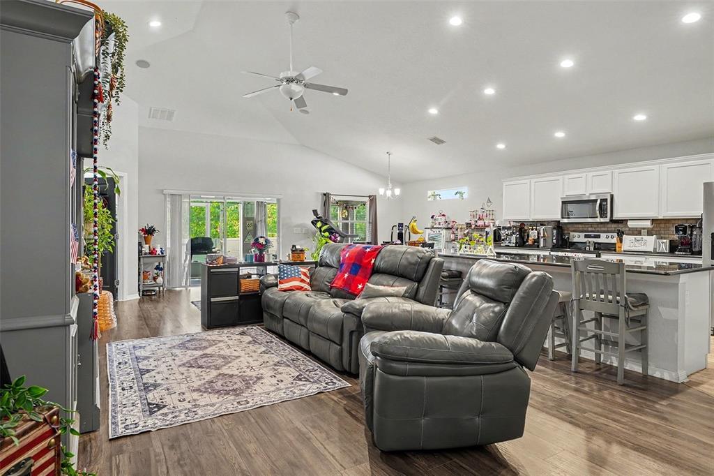 A living room with gray leather furniture, a patterned rug, and an open-concept kitchen — 2061 NIGHTHAWK DRIVE, HAINES CITY, FL