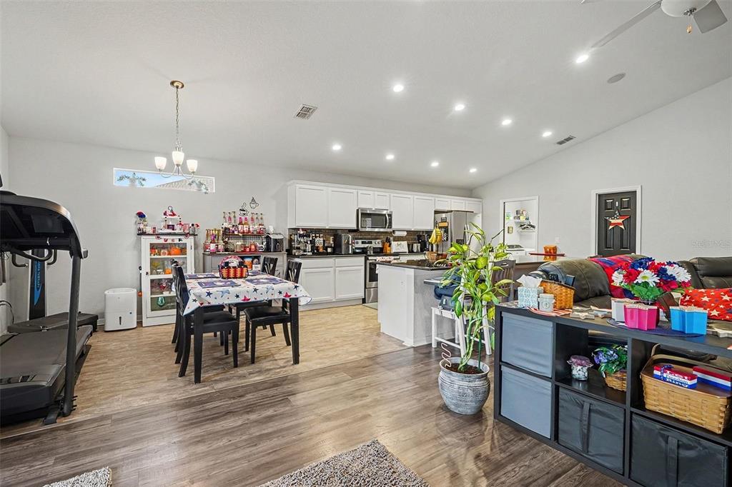 An open-concept kitchen and dining area features white cabinetry, a center island, and wood flooring — 2061 NIGHTHAWK DRIVE, HAINES CITY, FL