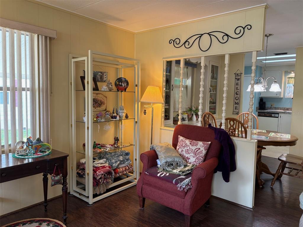 A living room with a red armchair, a glass display shelf, and a dining area beyond — 6033 GRAND OAKS DRIVE SE, WINTER HAVEN, FL