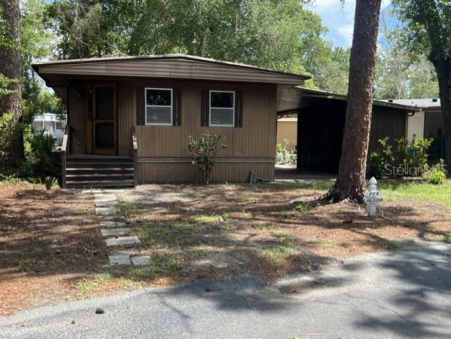 A brown mobile home features a front porch, a carport, and a stone walkway — 223 PEPPERTREE COURT, LAKE MARY, FL