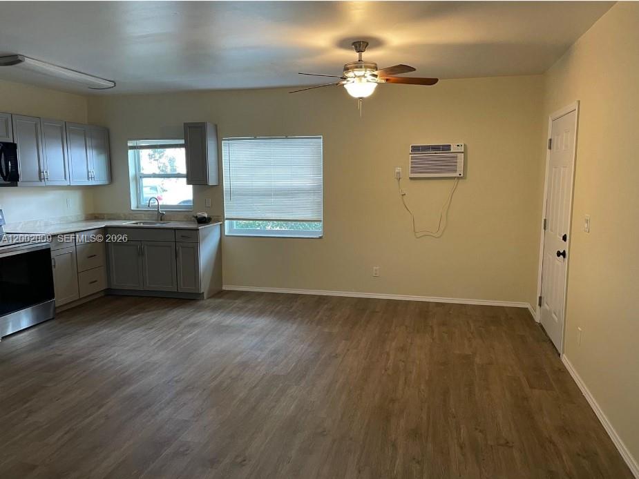 This kitchen features gray cabinets, wood-look flooring, a ceiling fan, and a wall-mounted air conditioner — 1720 Pierce St # 1, Hollywood FL 33020, HOLLYWOOD, FL