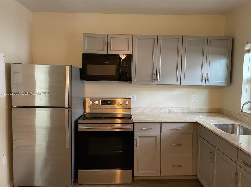 A kitchen features stainless steel appliances, light gray cabinets, and tan countertops — 1720 Pierce St # 1, Hollywood FL 33020, HOLLYWOOD, FL