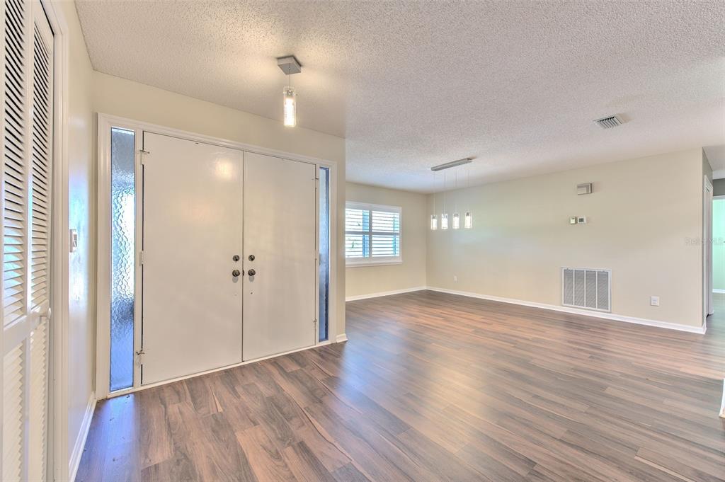 An entryway with double doors, wood-look flooring, and a dining area with pendant lighting — 1812 NEW BEDFORD DRIVE, SUN CITY CENTER, FL