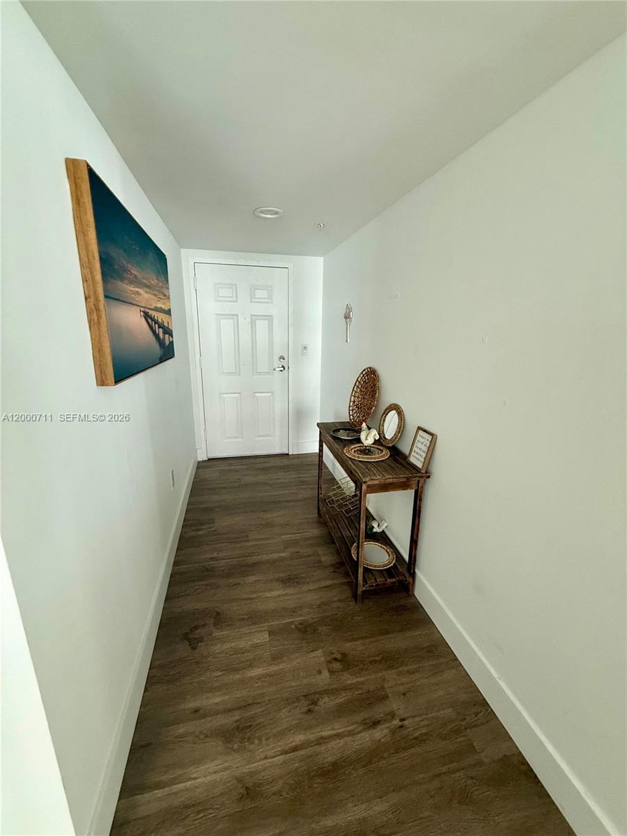 A narrow entryway features wood-look flooring, a white door, and a wooden console table — 1155 Brickell Bay Dr # 1702, Miami FL 33131, MIAMI, FL