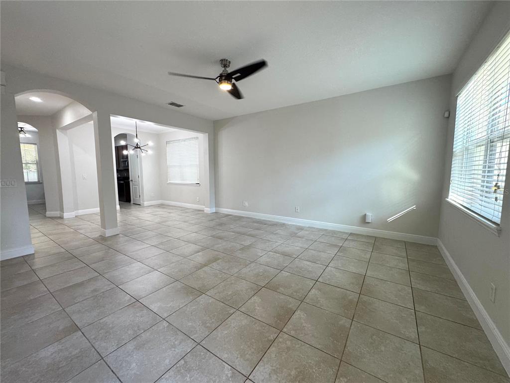 An open-concept living area features light-colored tile flooring, neutral walls, and a ceiling fan — 12784 GARRIDAN AVENUE, WINDERMERE, FL