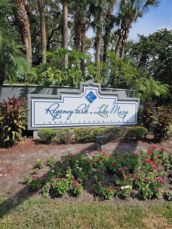 A sign for Regency Park at Lake Mary Luxury Condominiums stands amidst landscaping and trees — 711 SUGAR BAY WAY UNIT 115, LAKE MARY, FL