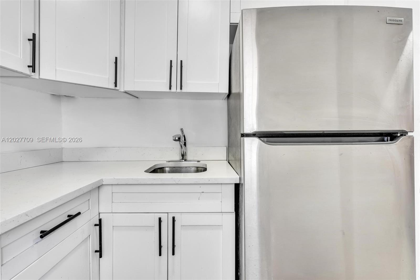 A small kitchen features white cabinets, a stainless steel refrigerator, and a white countertop — 1000 NW 95th Ter # 103, Miami FL 33150, MIAMI, FL
