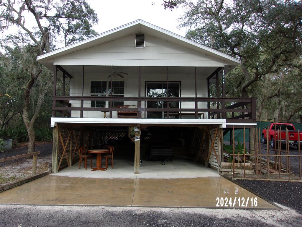 An elevated house with a screened porch, a concrete ground-level patio, and a red truck — 17935 SE 10TH PLACE, SILVER SPRINGS, FL