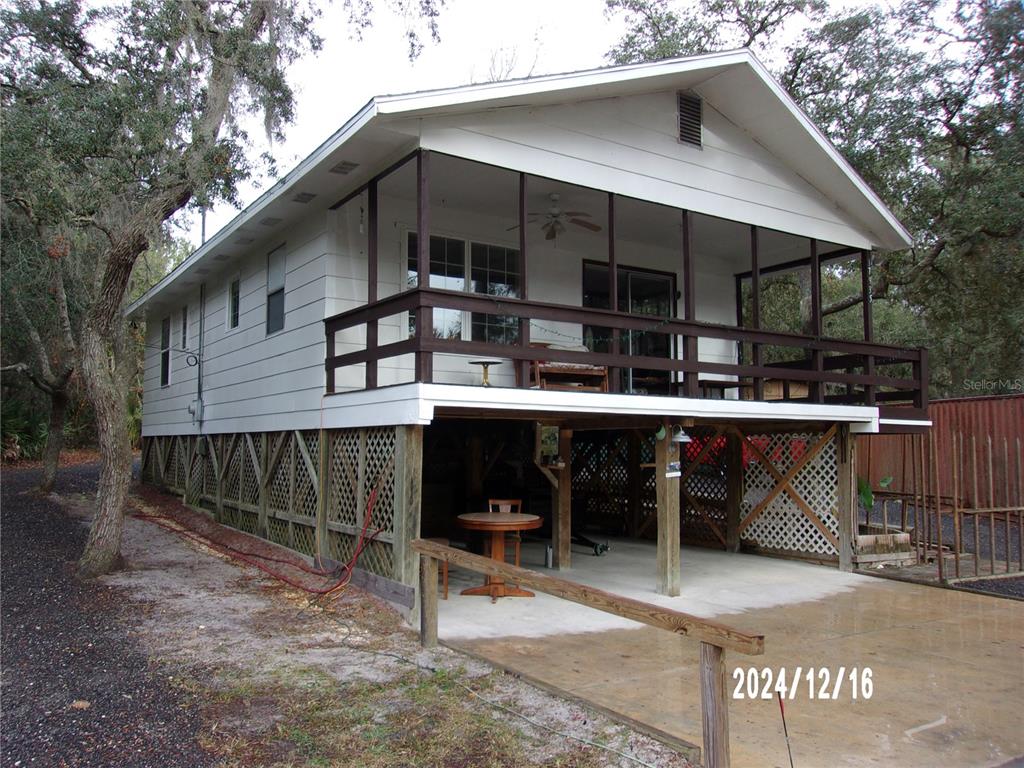 An elevated house with a screened-in porch, lattice skirting, and a concrete parking area underneath — 17935 SE 10TH PLACE, SILVER SPRINGS, FL