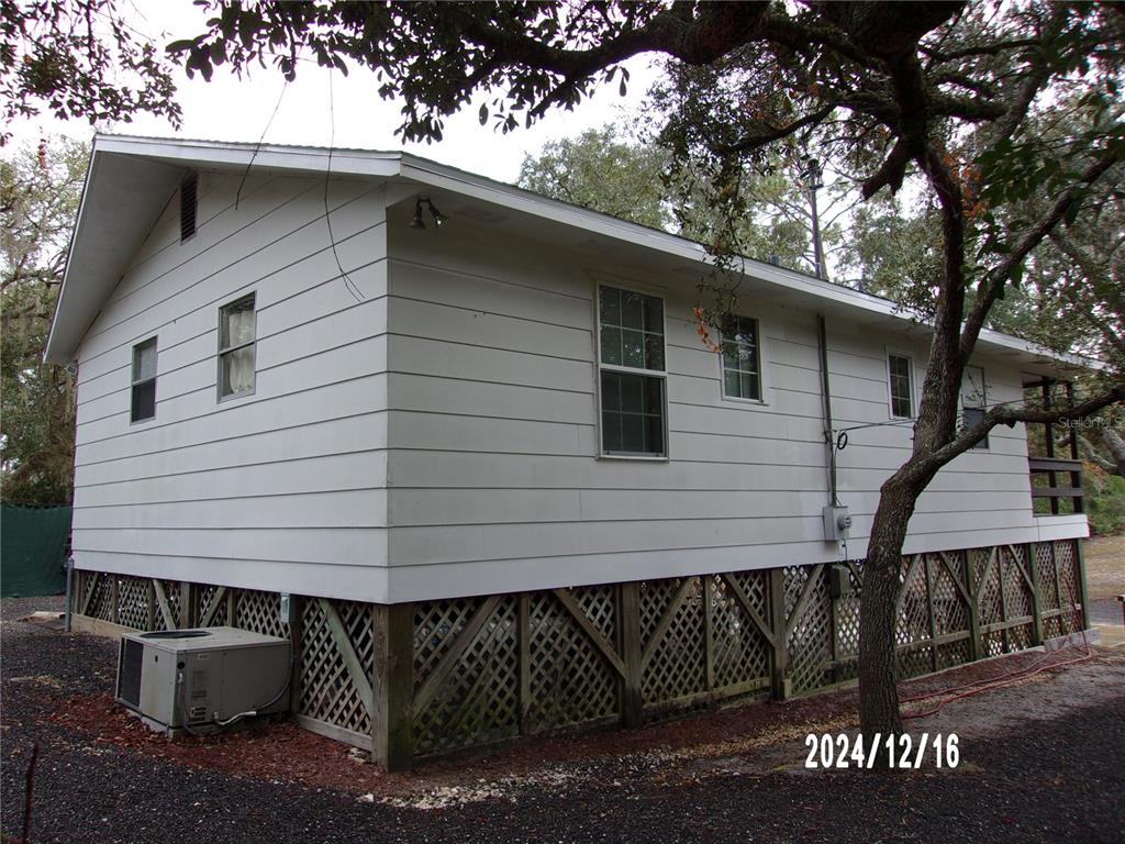 The exterior of a white, elevated house features lattice skirting and a ground-level air conditioner — 17935 SE 10TH PLACE, SILVER SPRINGS, FL