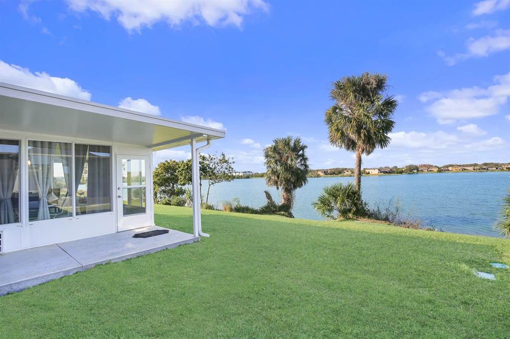 A view of a grassy backyard with a patio and a lake in the background — 8614 TURNSTONE SHORE LANE, RIVERVIEW, FL